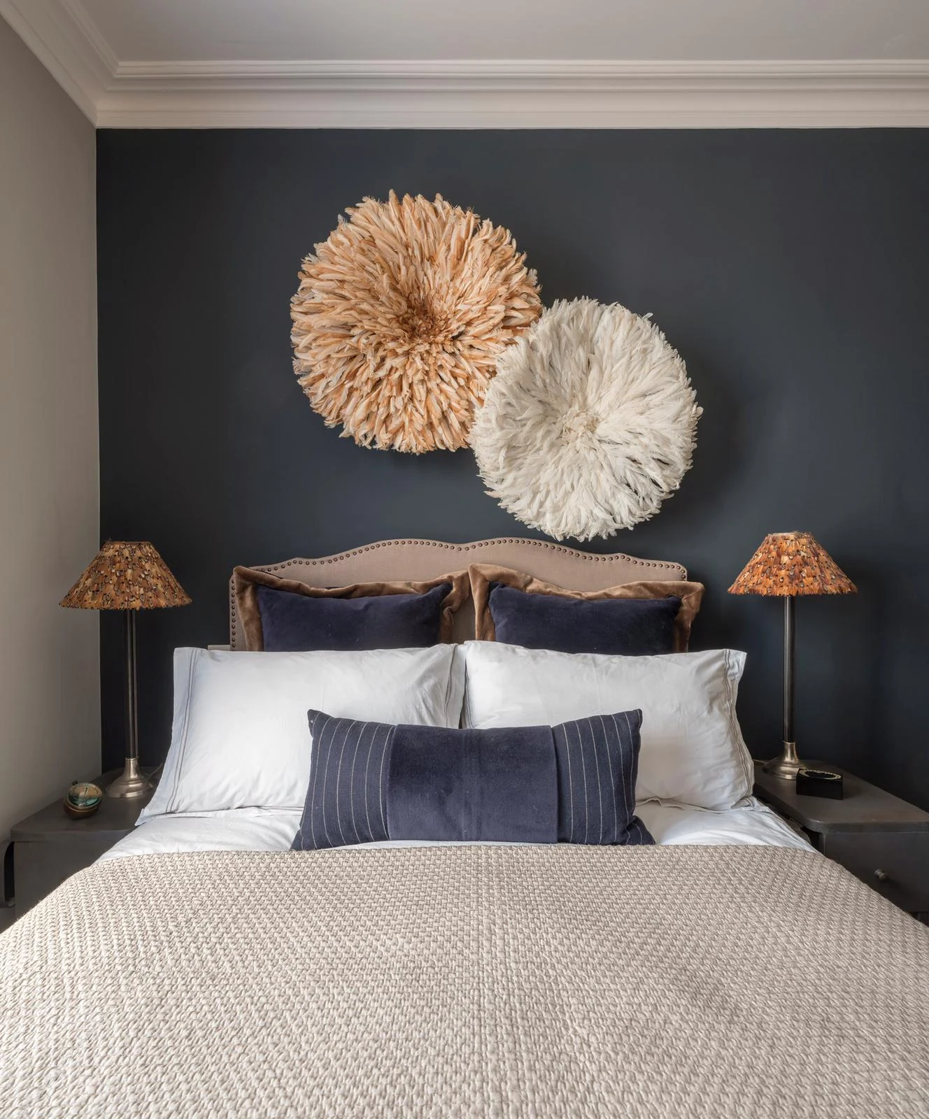Clapham guest bedroom with a dark wall, juju hat wall art and bedside lamps.