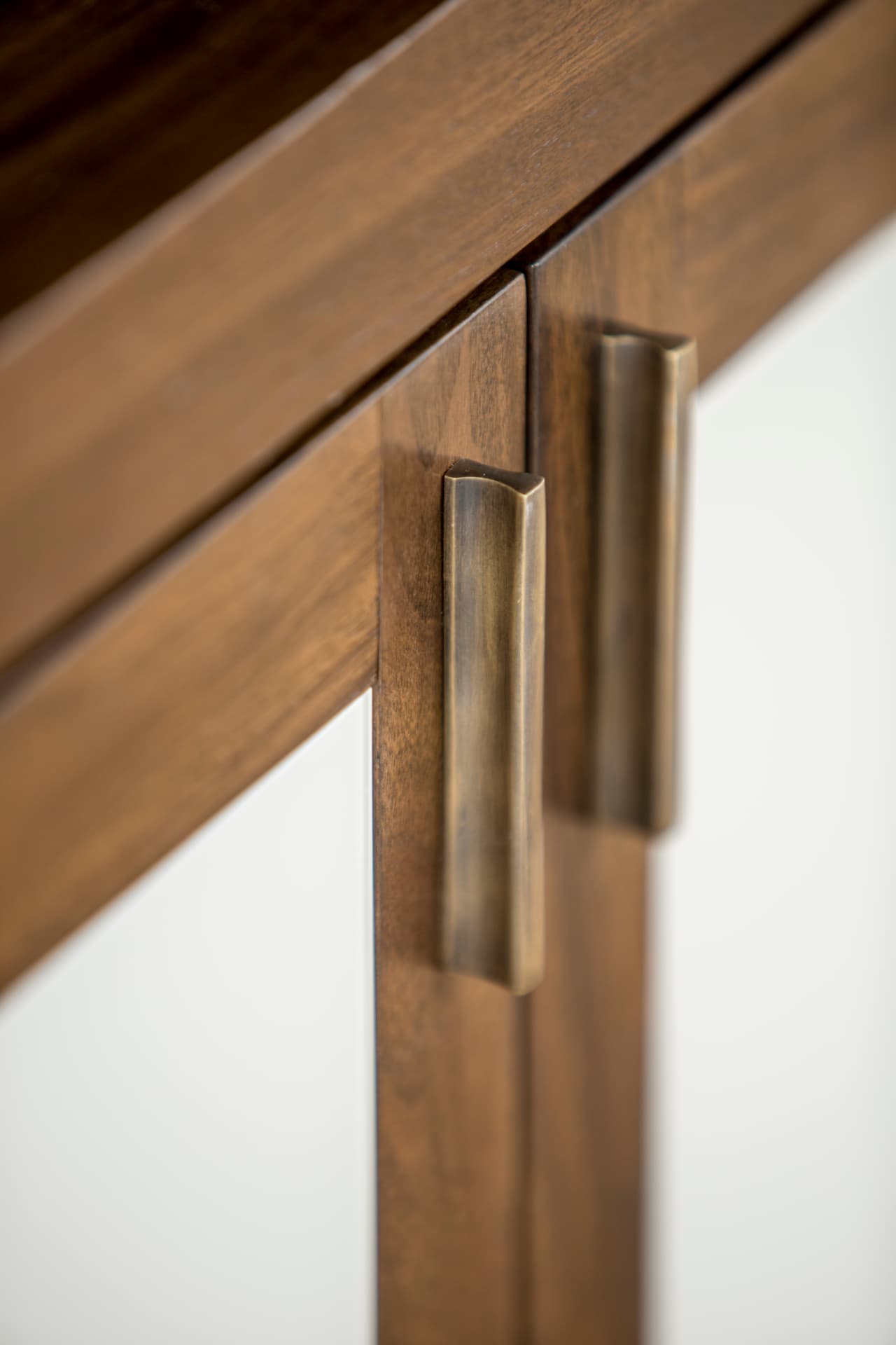 Close detail of bronze handles on walnut and lacquer joinery.