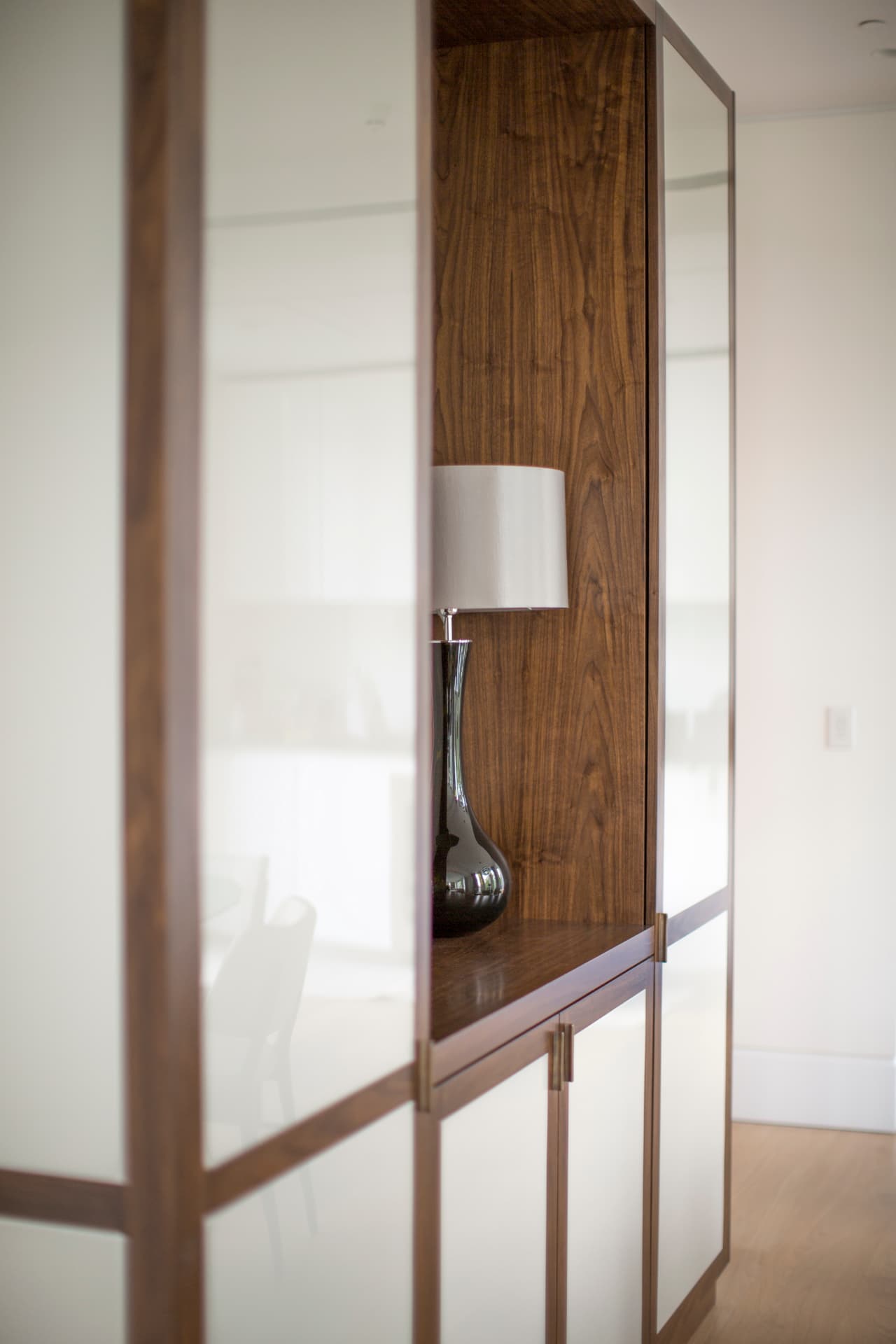 Walnut-framed joinery with a glass table lamp at Holland Park.