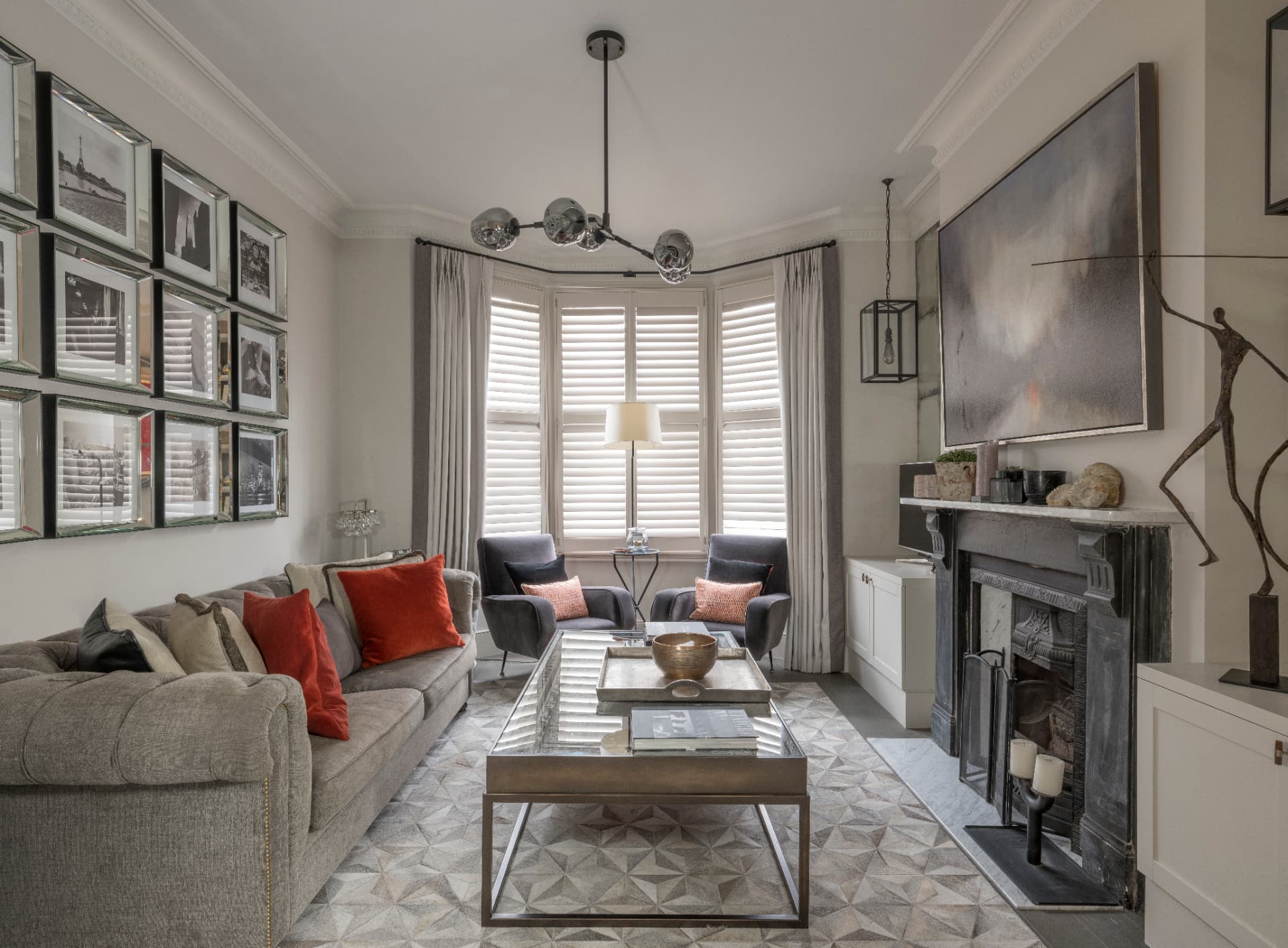 Clapham sitting room with a bay window, photograph wall and black marble fireplace.