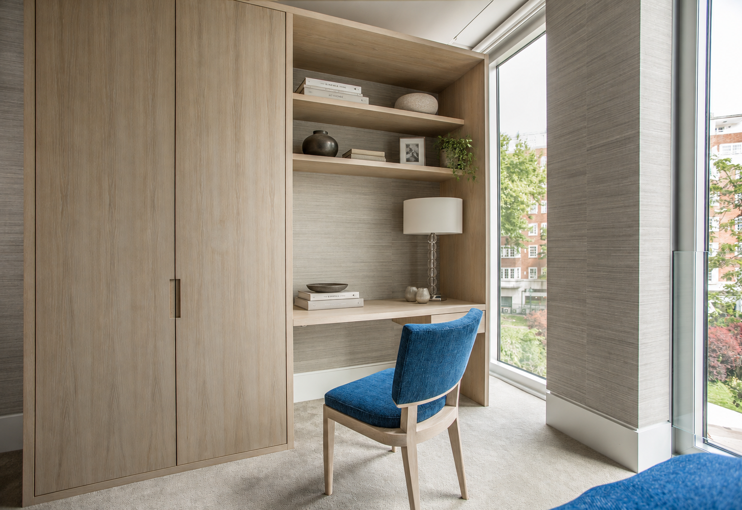 Bespoke pale timber joinery, a built-in desk and blue upholstered chair at Holland Park.