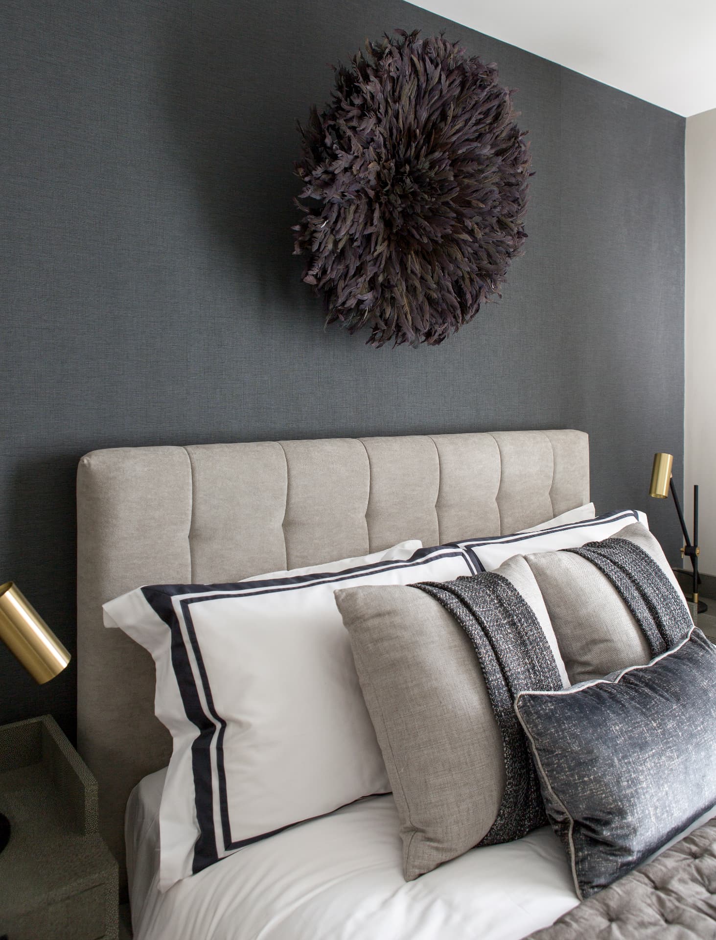 Detail of layered cushions against the charcoal bedroom wall.