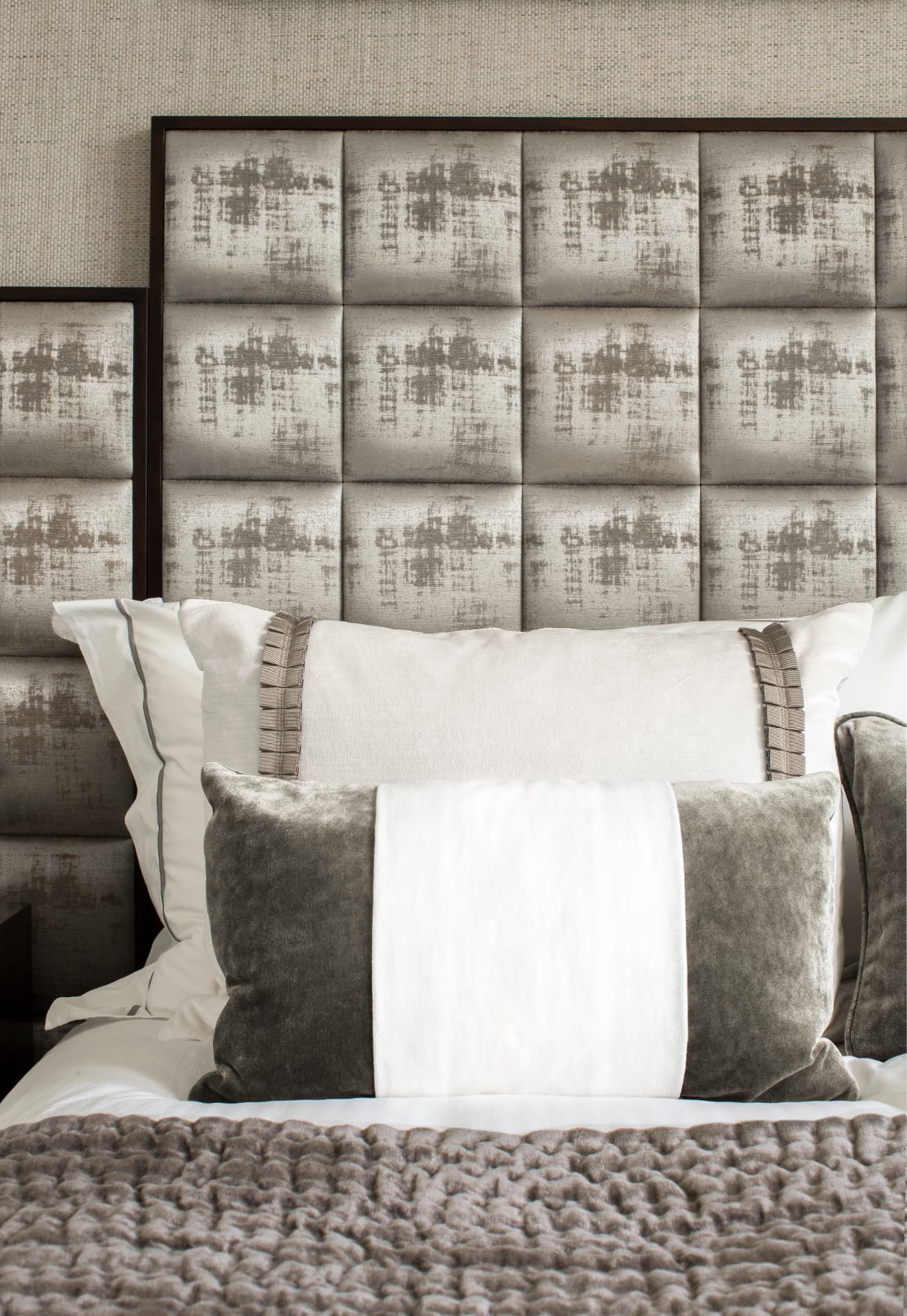 Detail of the panelled headboard, layered cushions and knitted throw.