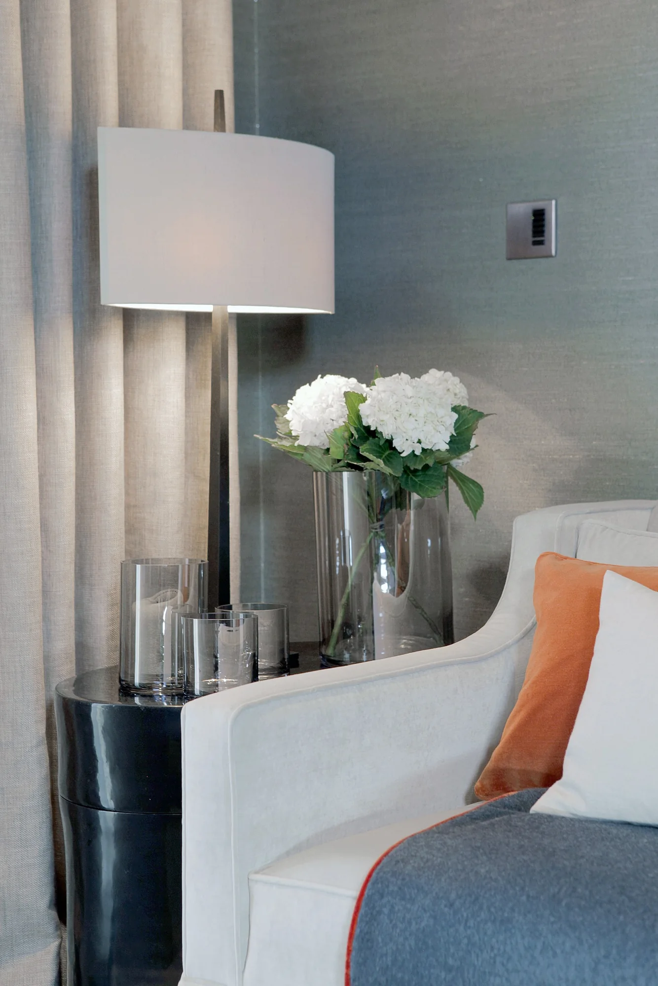 Sculptural table lamp and flowers beside the reception room sofa.