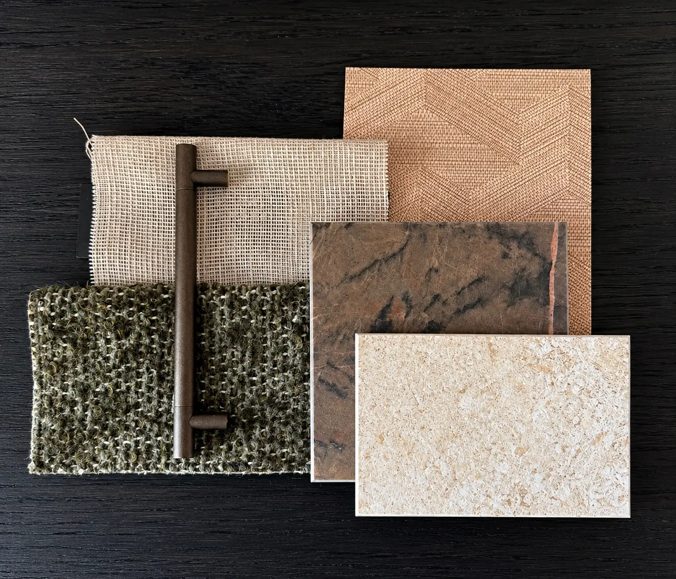A materials and finishes selection with linen, woven textiles, a bronze pull and stone samples.
