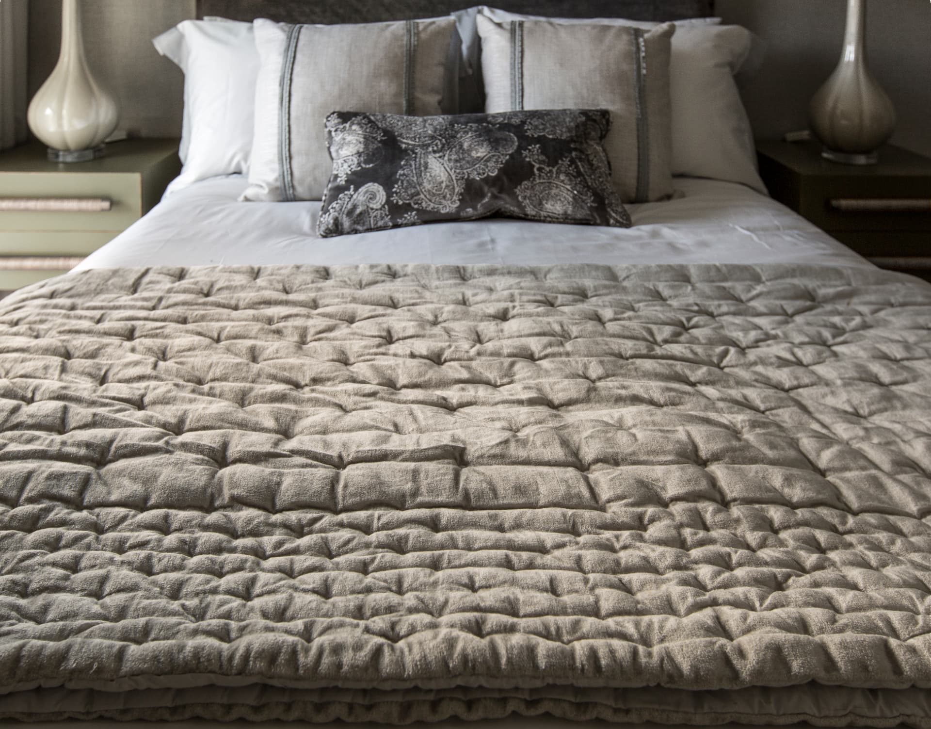 A quilted velvet bedspread and linen cushions in a Grosvenor Waterside bedroom.