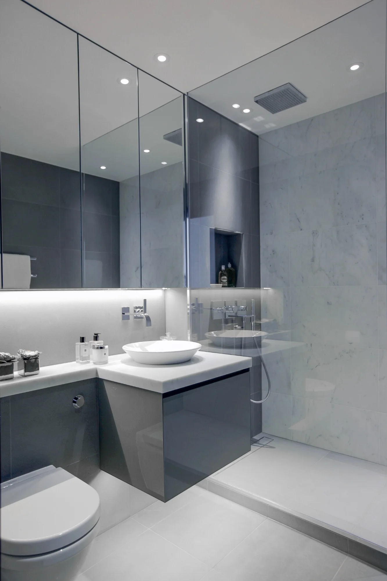 Bathroom with a tailored grey vanity and reflective surfaces.