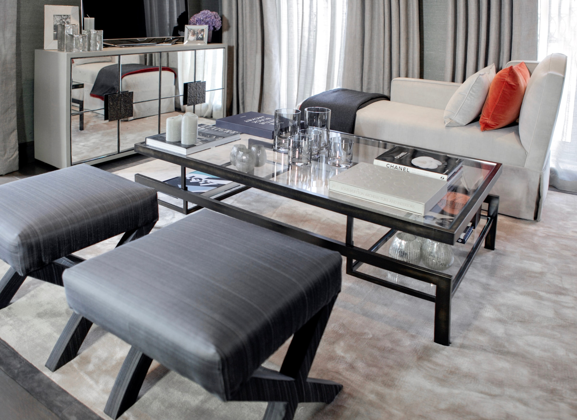 Kensington Green living room with a glass coffee table and upholstered stools.