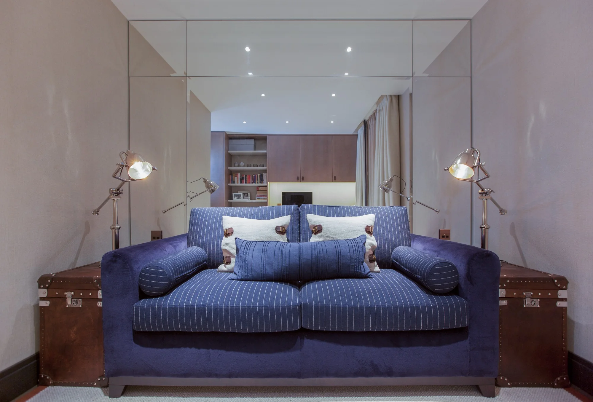 Blue upholstered sofa framed by mirrored walls in the family lounge.